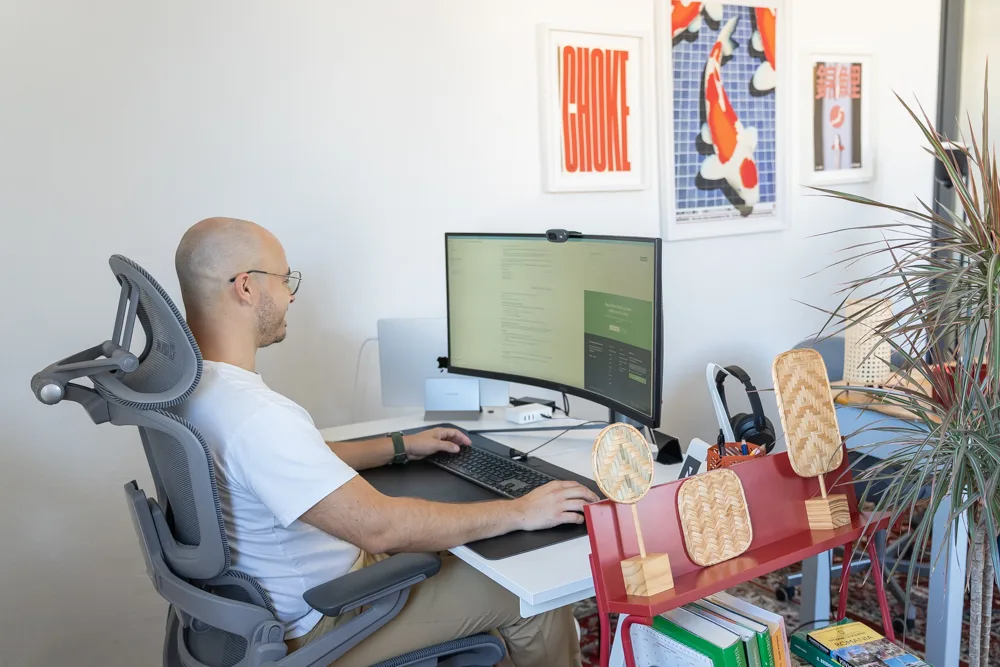 Francesco Nocentini di profilo alla scrivania davanti al monitor curvo, fotografia Koral
