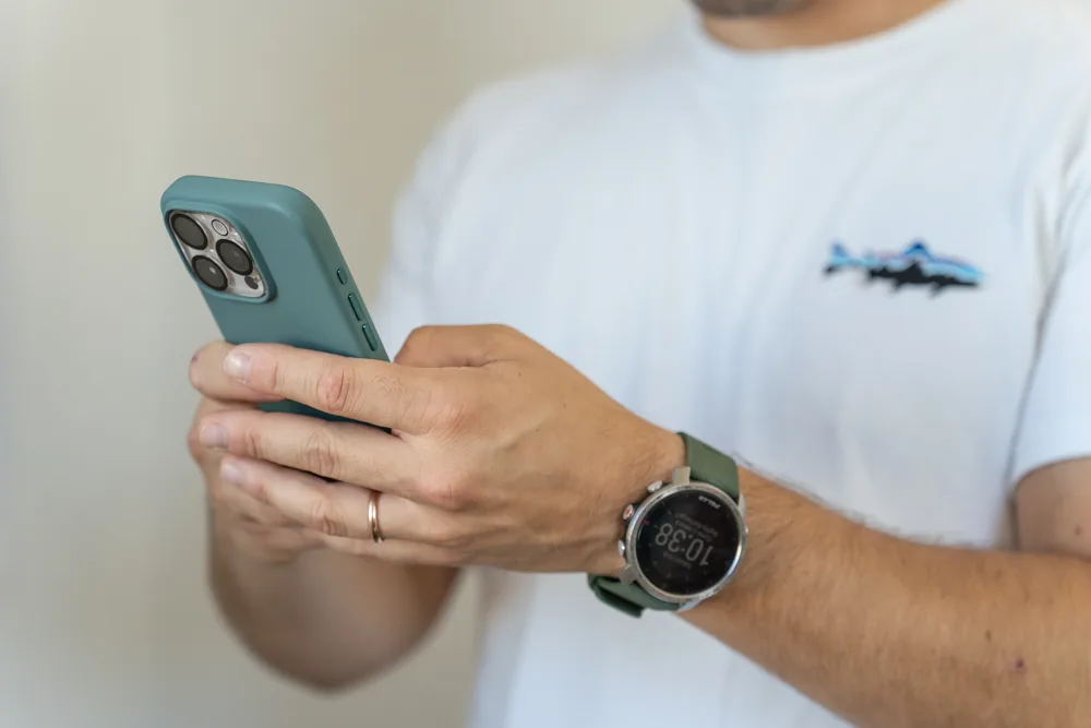 Dettaglio delle mani che tengono lo smartphone, con l’orologio al polso