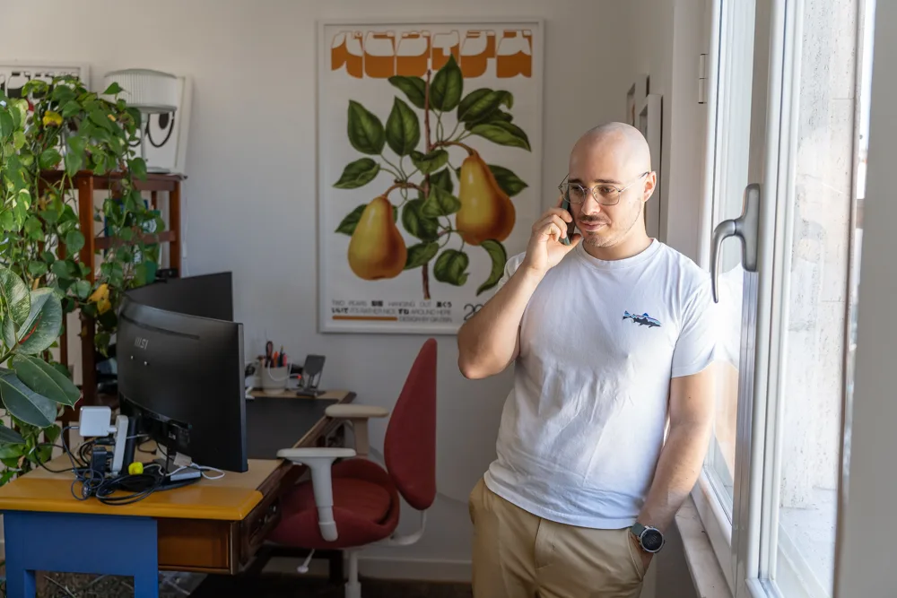 Francesco Nocentini al telefono alla finestra, con la scrivania sullo sfondo
