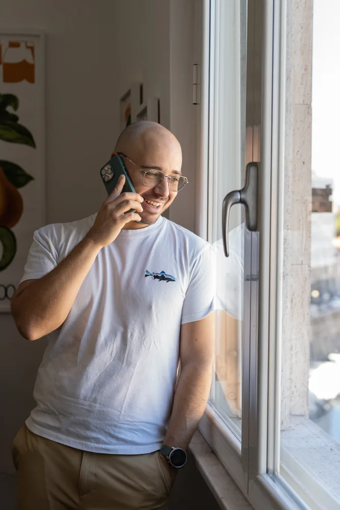 Francesco Nocentini sorride al telefono, controluce davanti alla finestra