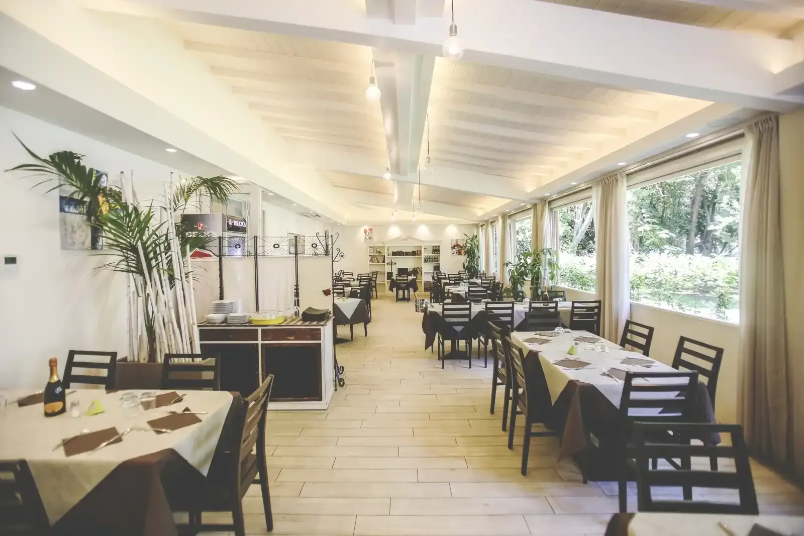 Sala colazione dell'Hotel Massimo a Viareggio, tavoli apparecchiati e vetrate sul verde, fotografia Koral