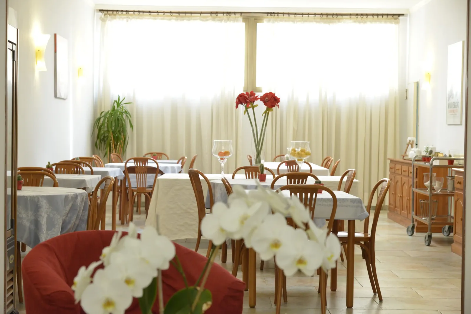 Sala interna dell'Hotel Massimo con tavoli apparecchiati e composizione di orchidee, scatto Koral