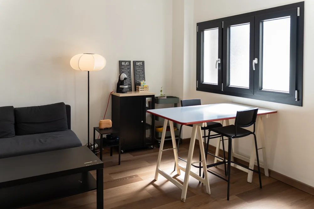 Tavolo alto con sgabelli davanti alla finestra nella lounge di Le Mura 85 a Livorno