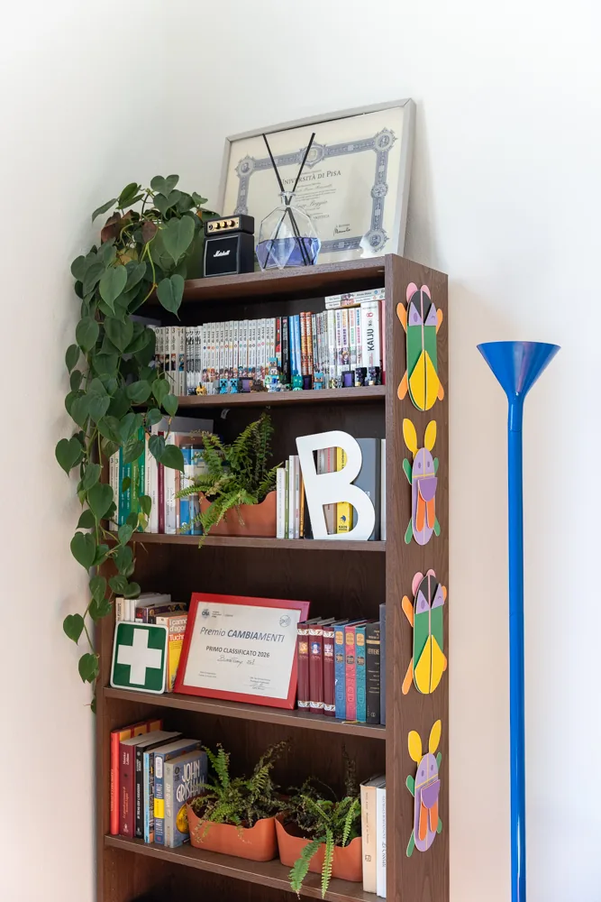 Libreria con attestati, piante e lampada da terra blu nella lounge
