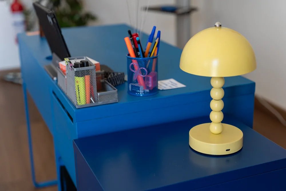 Dettaglio della scrivania blu con lampada gialla e portapenne
