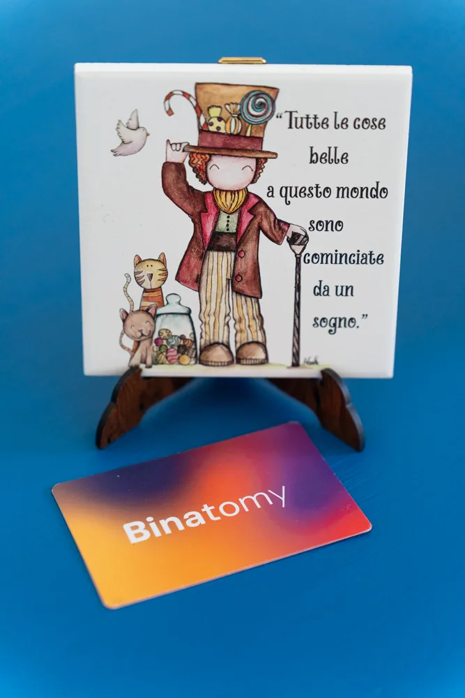 Piastrella illustrata con una citazione, appoggiata sulla scrivania blu