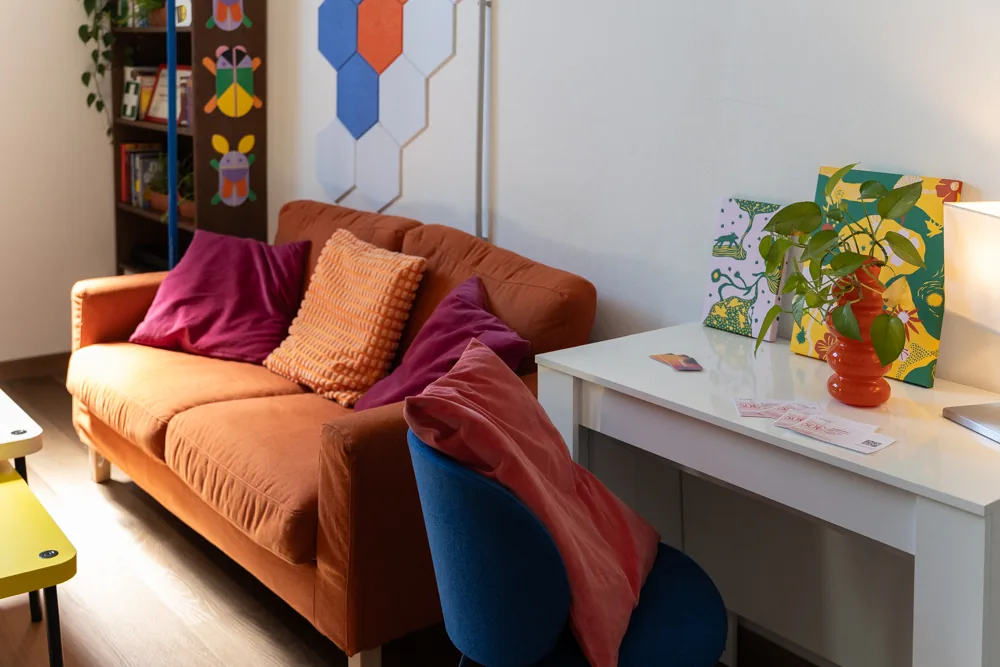 La lounge con il divano arancione e il tavolo bianco da lavoro