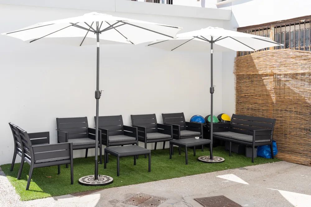 Il cortile esterno di Le Mura 85 con ombrelloni, sedute e prato sintetico