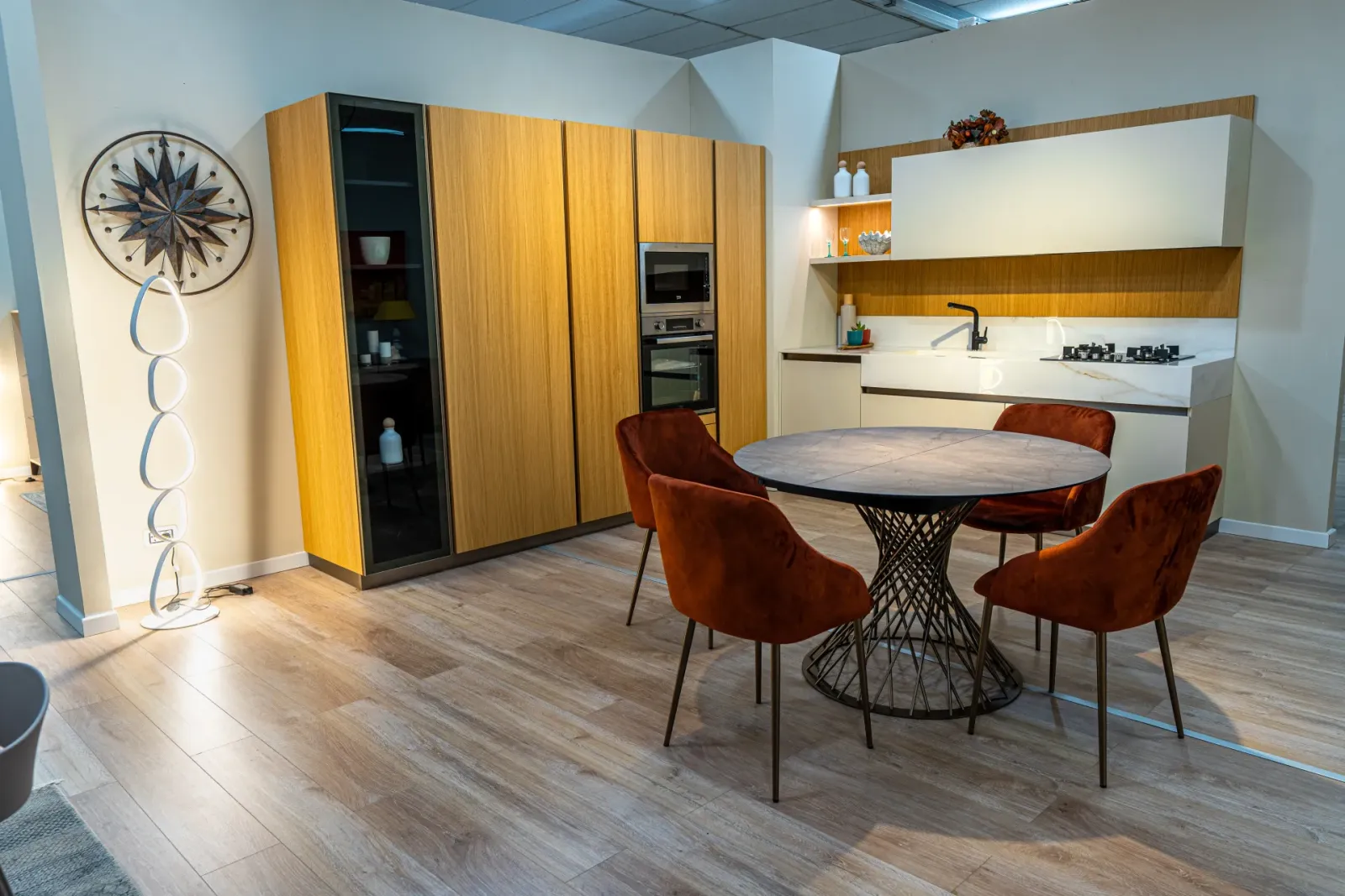 Cucina in legno e bianco con tavolo rotondo e sedie color ruggine, scatto Koral