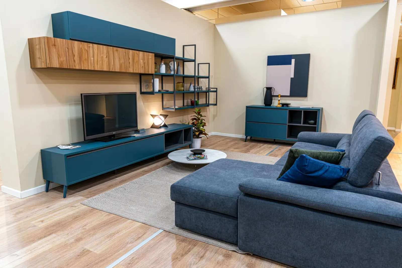 Salotto con composizione blu a parete e divano angolare grigio, fotografia Koral