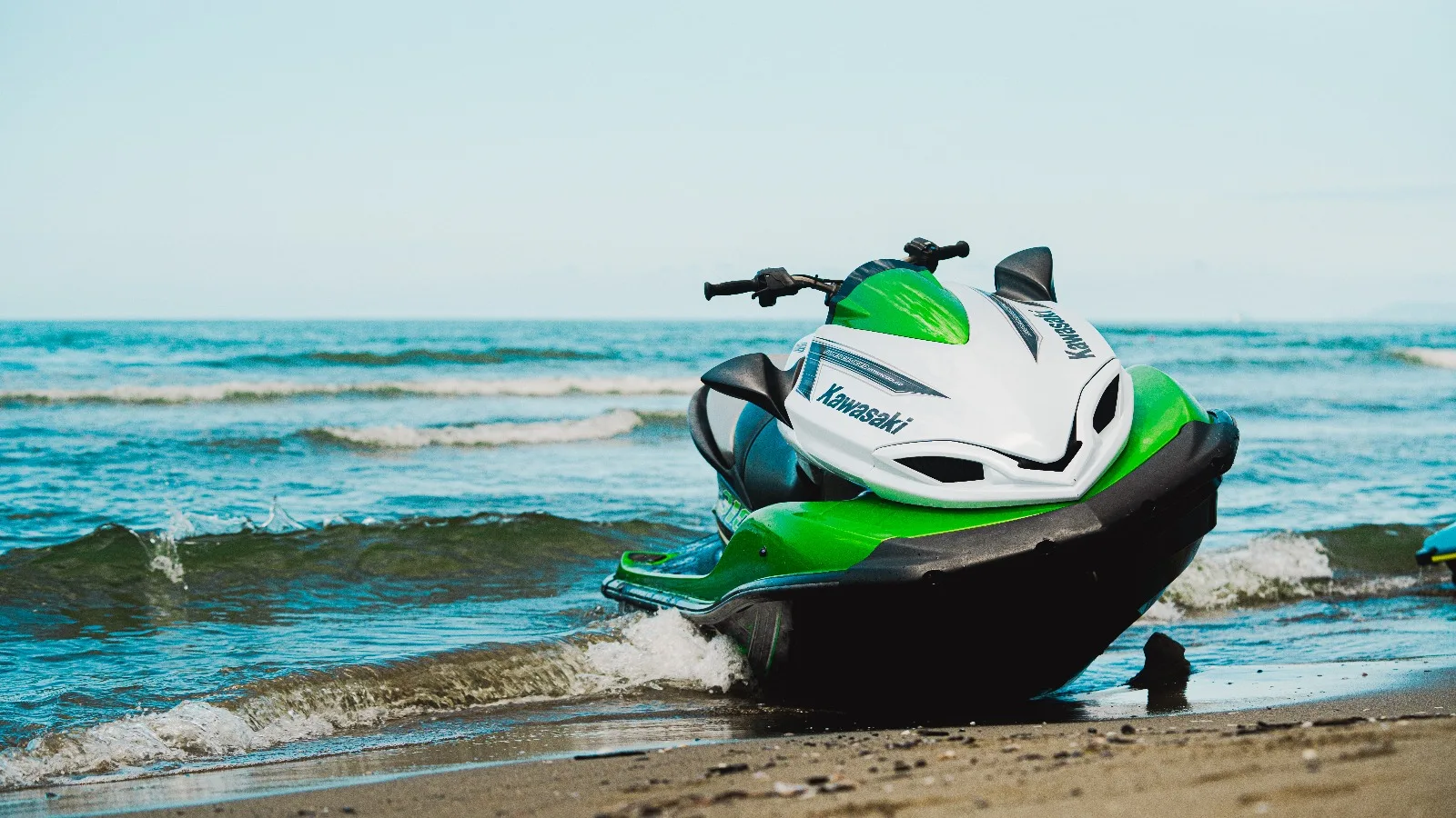 Moto d'acqua verde a riva con le onde che si infrangono, fotografia Koral