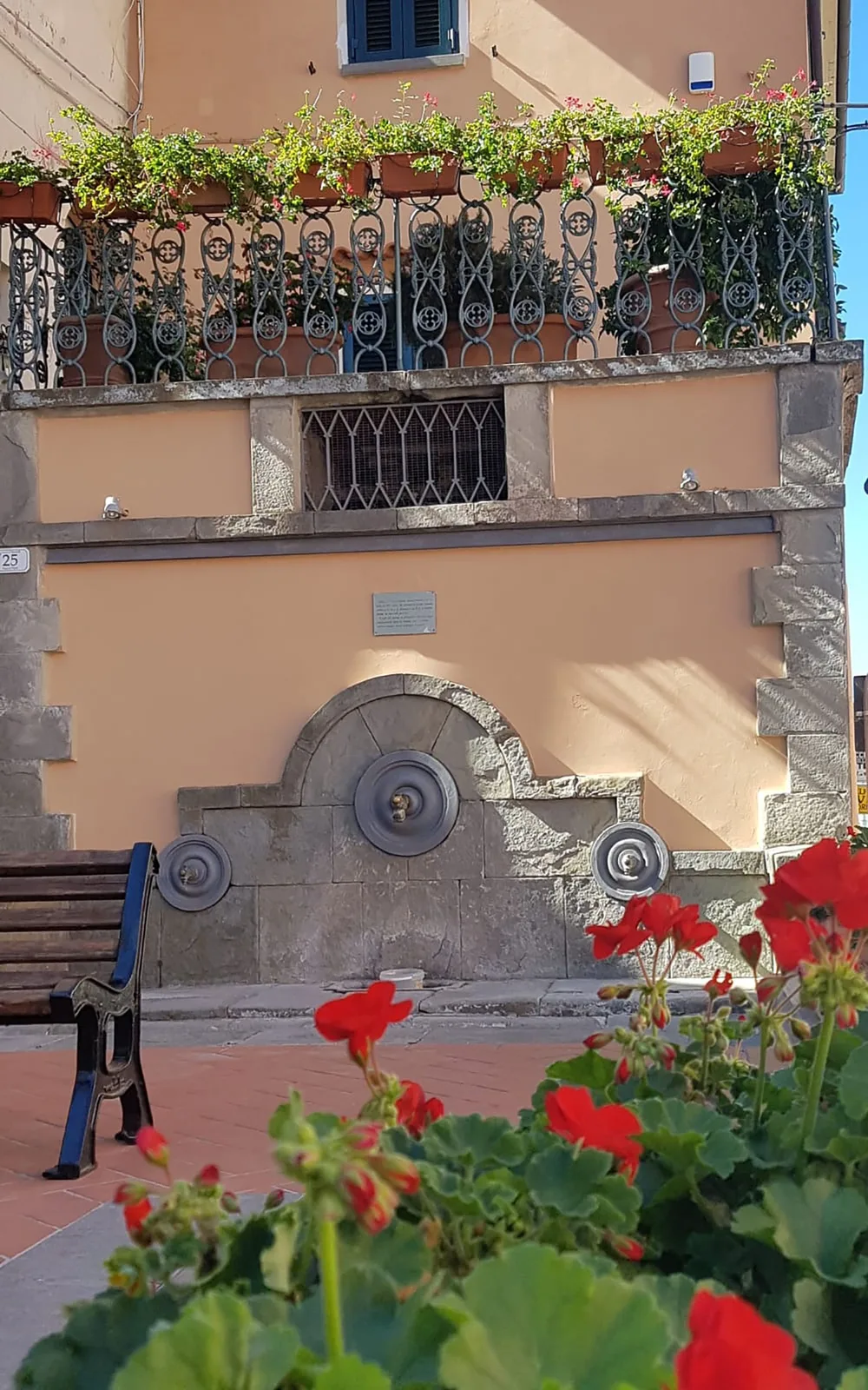 La fontana di Piazza del Popolo a Riparbella fra i gerani, immagine post-prodotta da Koral