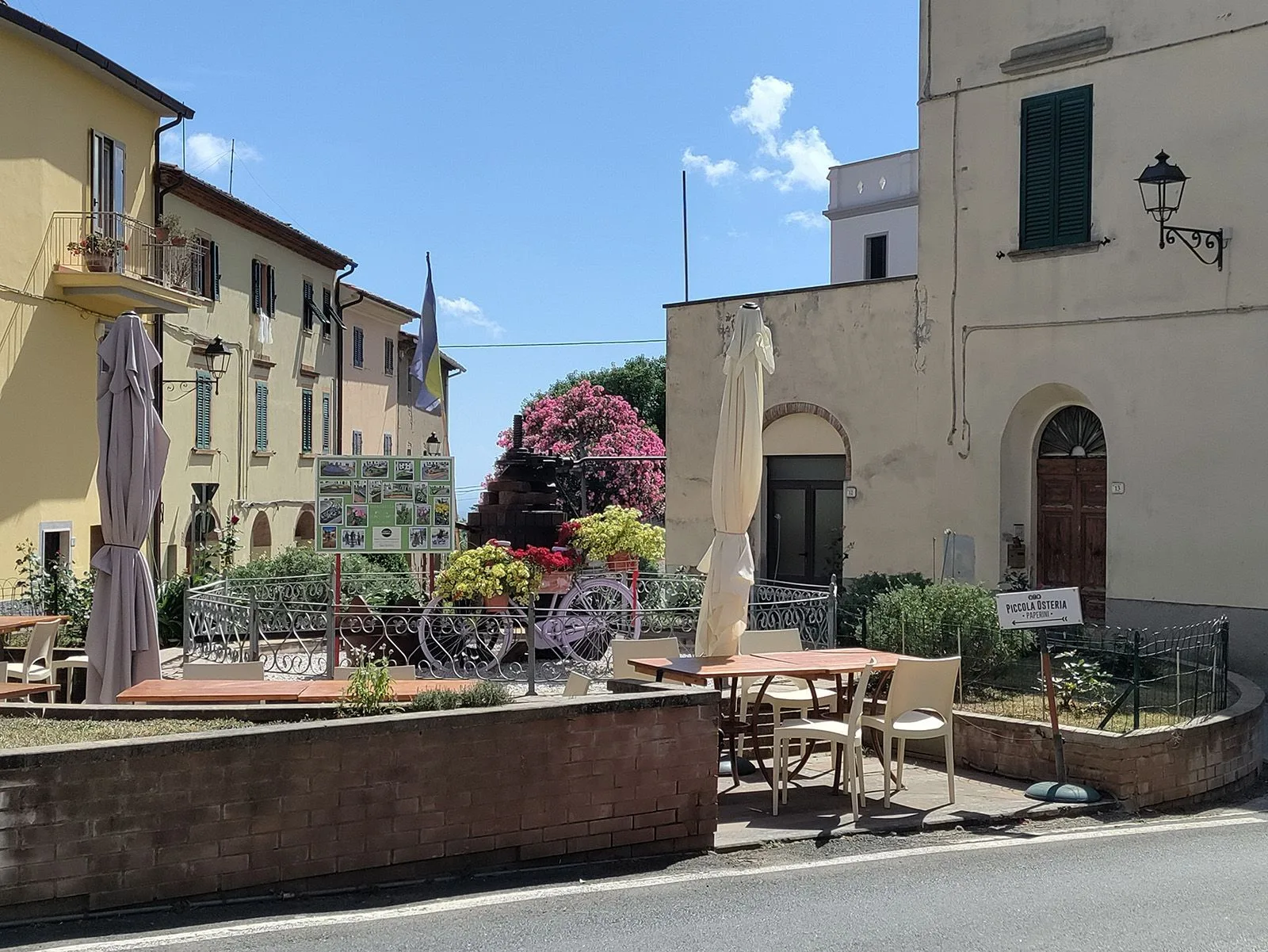 Piazza Baldasserini a Riparbella con la fontana e i tavolini, immagine post-prodotta da Koral