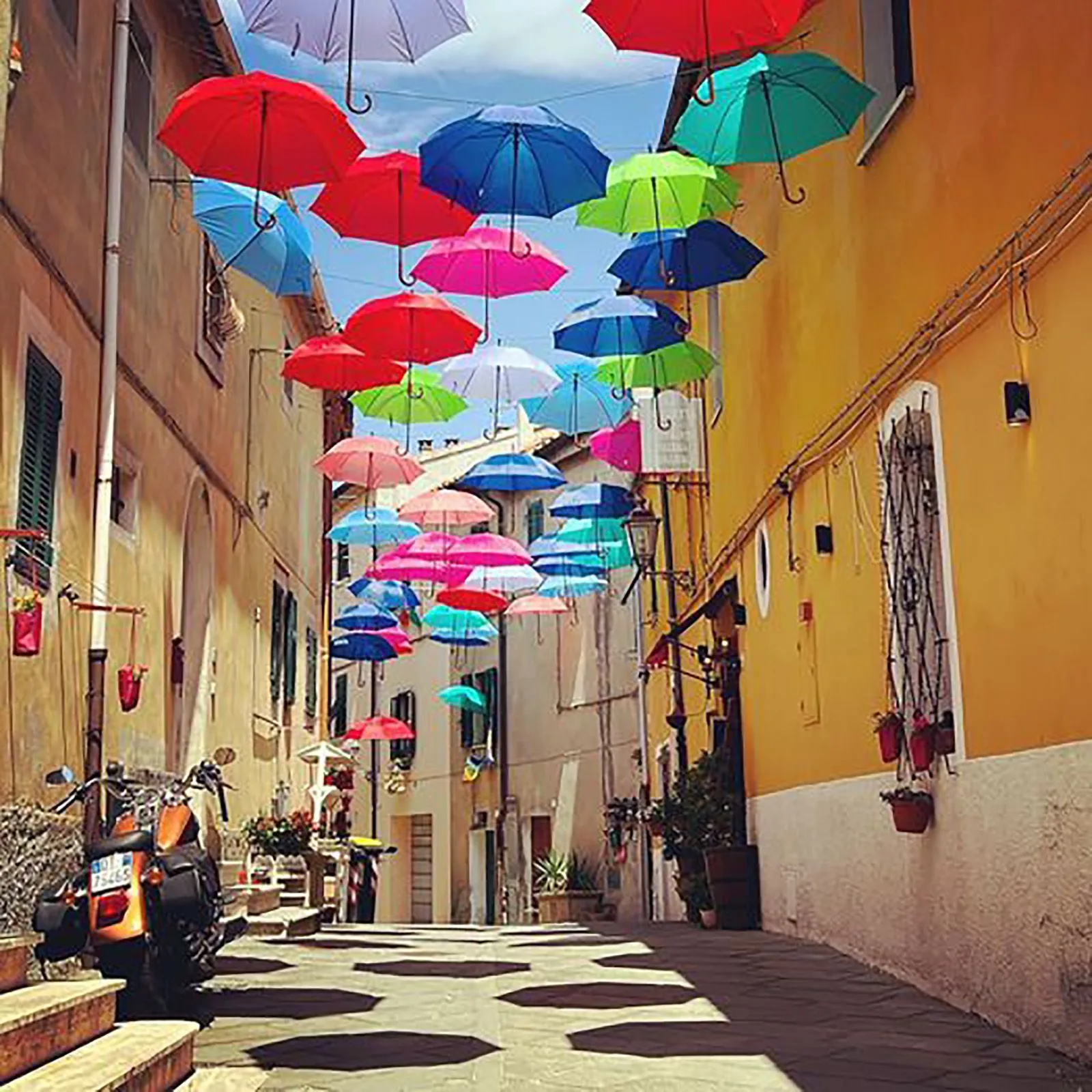 Via di Piazzetta a Riparbella con gli ombrelli colorati sospesi, immagine post-prodotta da Koral